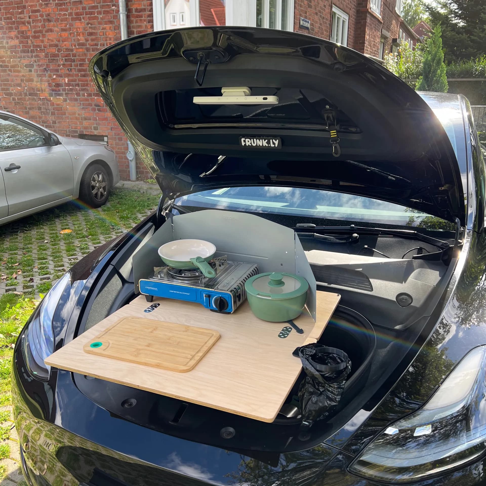 Tesla Model 3 Frunk gepackt mit Camping-Küchenausrüstung - Teller, Kocher, Wasserkessel und Frunkly-Tisch