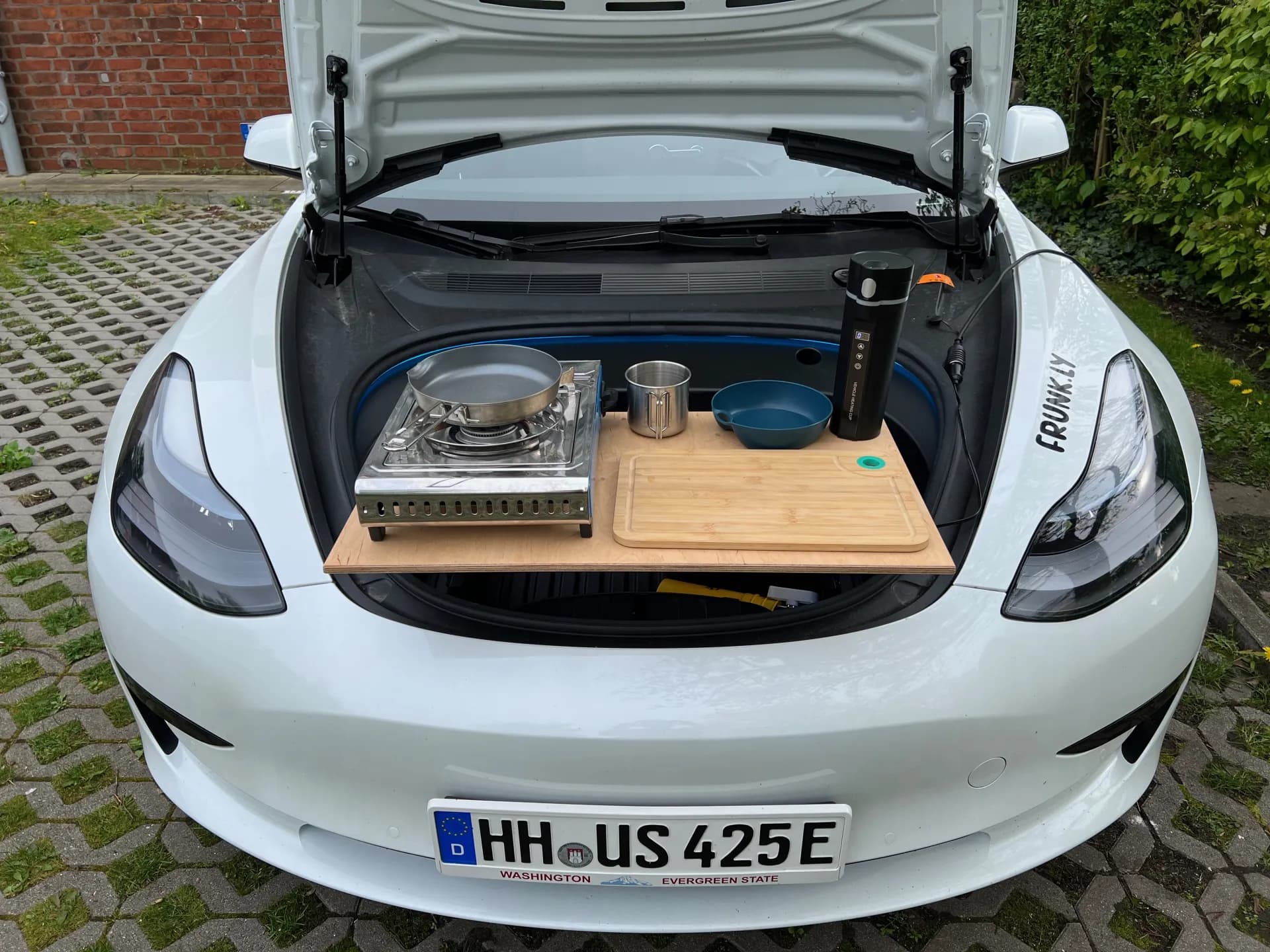 White Tesla Model 3 with Frunkly table on frunk showing camp stove, pan, and cooking accessories